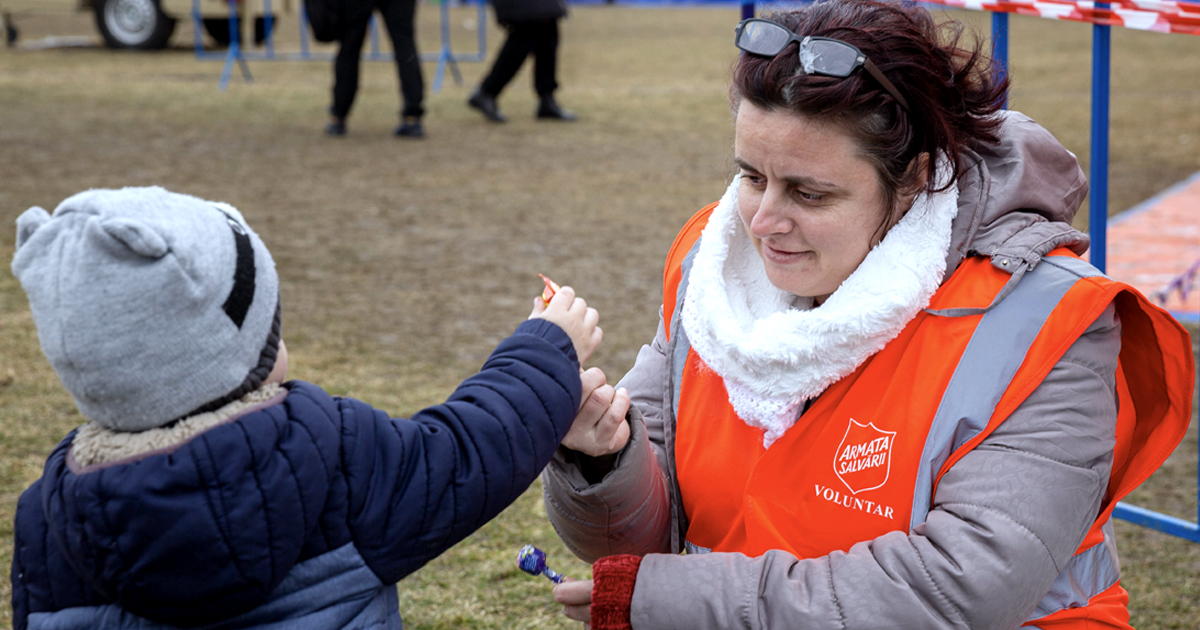 A Salvation Army worker provides assistance to a young refugee in Romania