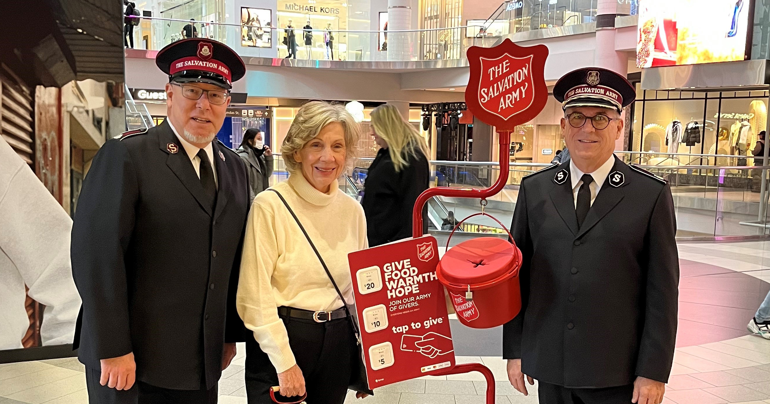 Susan Waterfield, a member of the National Advisory Board, rings kettle bells at the Eaton Centre in Toronto, accompanied by Lt-Col John Murray (left) and Commissioner Floyd Tidd, territorial commander
