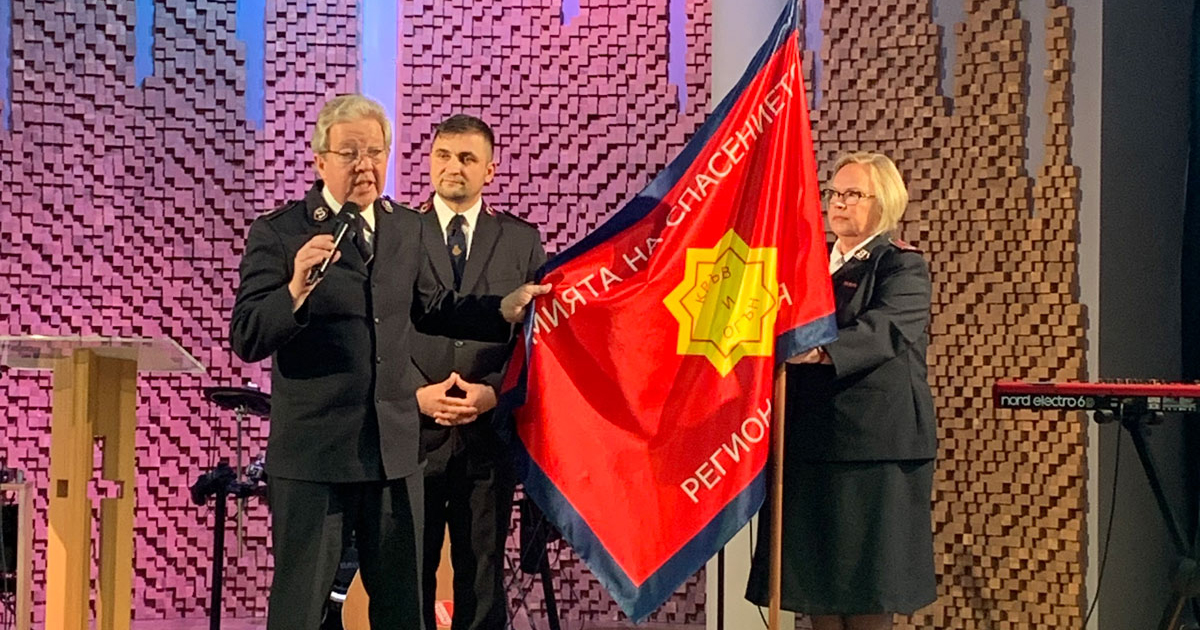 Comr Johnny Kleman presents the Salvation Army flag
